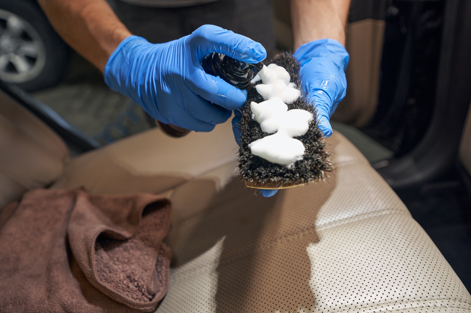 Detailing worker applies leather cleaning foam to brush